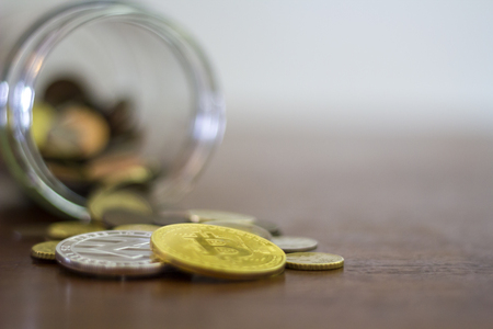 Cryptocurrency coins, Bitcoin and Litecoin, spilling from a glass jar. Copy spaceの写真素材