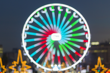 Defocused ferris wheel attraction illuminated at nightの写真素材