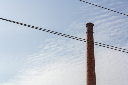 Brick chimney and electric wires against blue skyの写真素材