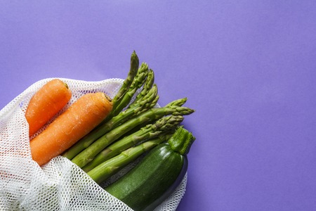 Top view of fresh vegetables on reusable bag with copy space on purple backgroundの写真素材