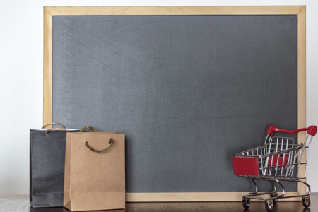 Shopping bags and shopping cart with blackboard on the background with copy spaceの写真素材