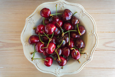 Bowl of cherries on wooden table. Top view