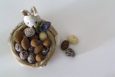 Easter Bunny basket with different chocolate eggs on white tableの写真素材