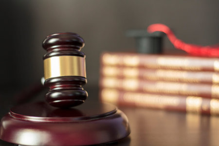 Judge's gavel with books and graduation cap on the background