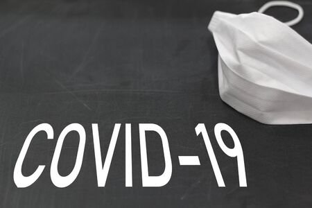 Face mask on blackboard with Covid-19 textの写真素材