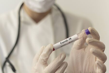 Doctor or nurse with gloves and respiratory face mask holding a positive blood test for Coronavirus Covid-19の写真素材