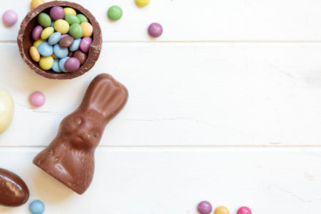 Top view of chocolate bunny and sweets on white wooden table with copy space
