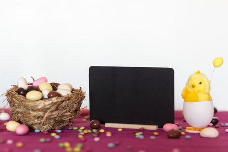 Bird nest with easter almond eggs, chick hatching from egg and blackboard with copy space