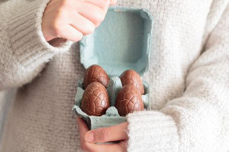 Woman hands holding egg carton with edible easter chocolate eggs inside