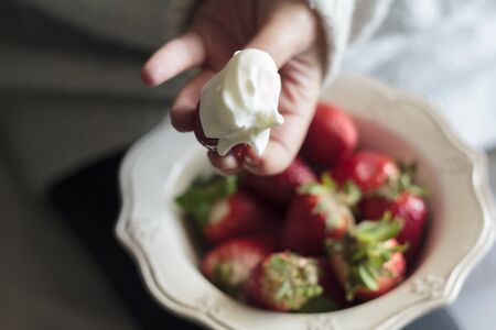 Woman holding strawberry with whipped creamの写真素材