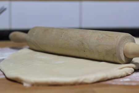 Raw dough and rolling pin on wooden boardの写真素材