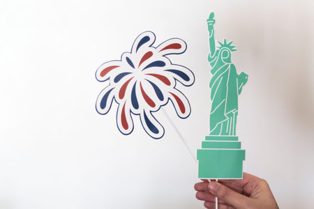 Woman hand holding statue of Liberty and firework props. USA holiday, 4 of July, celebration...
