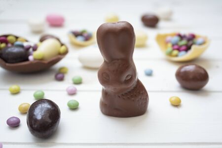 Chocolate bunny and easter eggs and sweets on white wooden tableの写真素材
