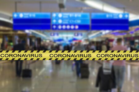Coronavirus warning tape with blurred airport image on the background. COVID-19 spread and restrictions conceptの写真素材