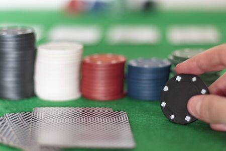 Hand holding poker chip on a green poker tabkeの写真素材