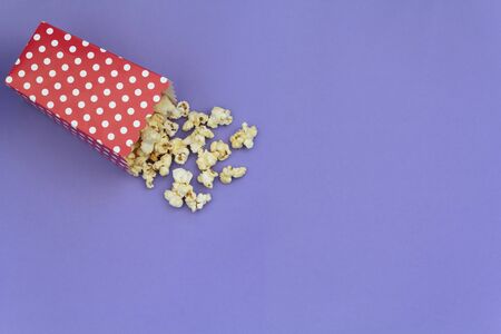 Red box with popcorns on purple background with copy spaceの写真素材