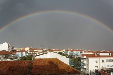 Full rainbow above buildingsの写真素材