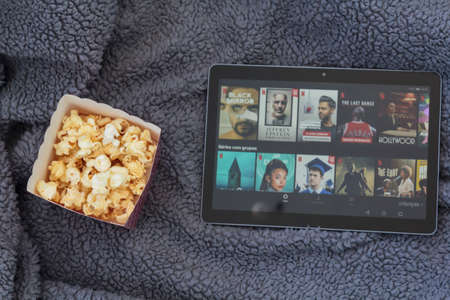 Lisbon, Portugal - CIRCA June 2020: Top view of popcorn box and tablet with netflix on warm blanketのeditorial素材