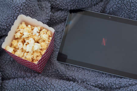 Lisbon, Portugal - CIRCA June 2020: Top view of popcorn box, tablet with netflix logo and fluffy blanketのeditorial素材