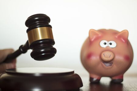 Judge hitting Judge's gavel with piggy bank on wooden table. Economic litigations and auctions conceptの写真素材