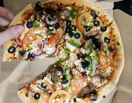 Top view of woman hand taking a slice of pizzaの写真素材