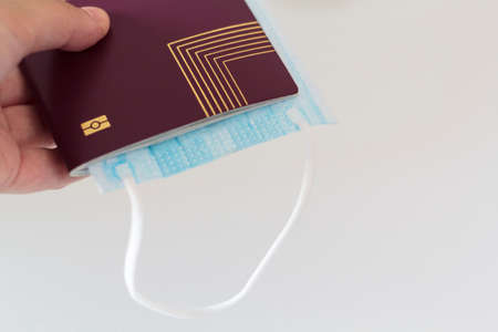 Hand holding passport and medical mask. Traveling during coronavirus, covid-19 pandemicの写真素材