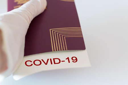 Hand with glove holding Passport and covid-19 note. Concept of Traveling during coronavirus, covid-19 pandemicの写真素材