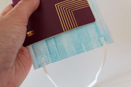 Hand holding passport and medical mask. Traveling during coronavirus, covid-19 pandemicの写真素材