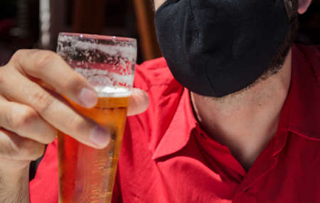 Men with protective face mask holding a beerの写真素材