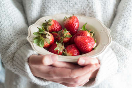 Woman holding vintage bowl with strawberriesの写真素材