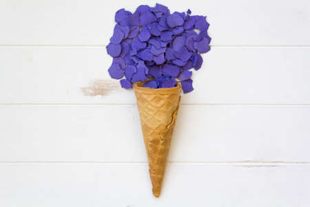Top view of ice cream cone with purple confetti on white wooden tableの写真素材