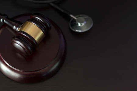 Judge's gavel and medical stethoscope on black wooden table with copy space. Medical lawsuit conceptの写真素材