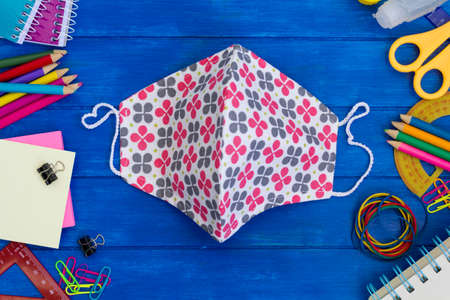 School supplies and cloth masks on blue wooden table. Back to school during covid-19 pandemic, new normal conceptの写真素材