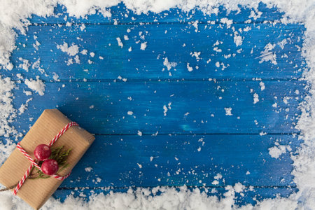Top view of christmas present and snow on blue wooden table with copy space