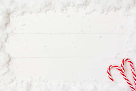Top view of candy cranes on snowy white wooden table. Top view with copy space. Christmas backgroundの写真素材
