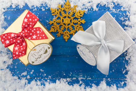 Top view of christmas gift boxes and decoration on snowy blue wooden tableの写真素材