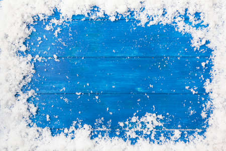 Top view of snow frame on blue wooden table with copy space. Winter or Christmas backgroundの写真素材