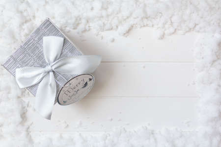 Top view of christmas gift box on snowy white wooden table with copy space. Christmas backgroundの写真素材
