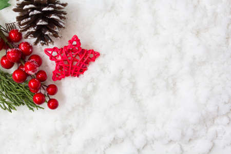 Holly berries, pine cone and star on snow. Winter holiday, christmas background. Top view with copy spaceの写真素材