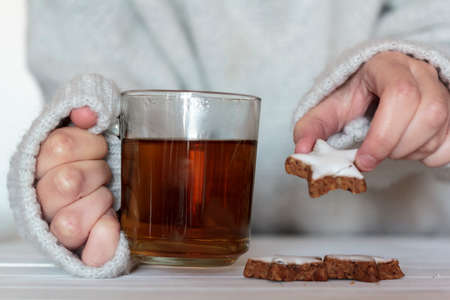 Woman hands holding a cup of tea and cookiesの写真素材