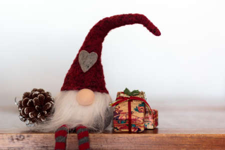 Christmas gnome with gift and pine cone on wooden table. With copy spaceの写真素材