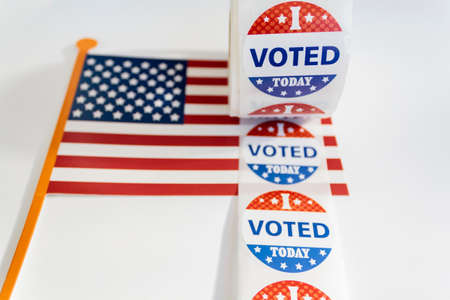 Roll of I Voted Today stickers and USA flag on white background. US presidential election conceptの写真素材