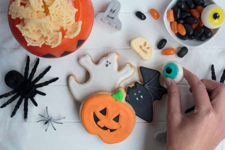 Woman's hand holding a halloween eye, on table with other halloween treatsの写真素材