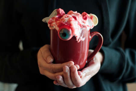 Woman holding mug with spooky halloween drinkの写真素材