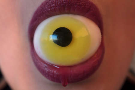 Close-up of woman with eyeball on the mouth dripping blood. Halloween conceptの写真素材