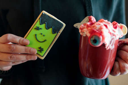 Woman holding halloween monster cookie and spooky drinkの写真素材