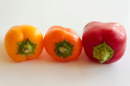 Red pepper, orange pepper and yellow pepper on white backgroundの写真素材