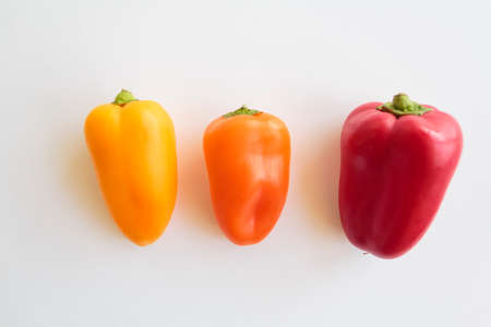 Top view of Red pepper, orange pepper and yellow pepper on white backgroundの写真素材