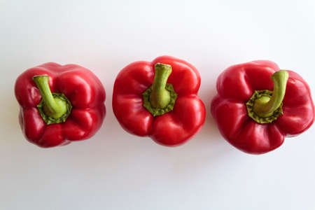 Top view of three red peppers in line on white backgroundの写真素材