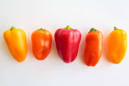 Red pepper, orange pepper and yellow pepper on white backgroundの写真素材